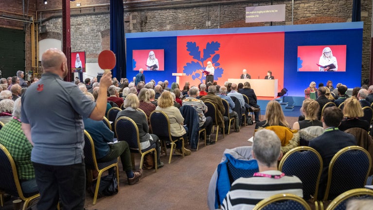 A man holding up a voting plaque at the AGM event